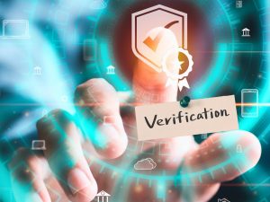 Finger tippt auf Bildschirm für den Blauen Haken Instagram und darunter hängt ein Schild mit der Aufschrift "Verifizierung"